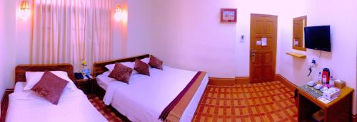 a hotel room with two beds and a television at Inle Star Hotel in Nyaungshwe Township