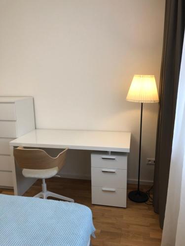 a white desk with a lamp and a chair at Apartment DOWNTOWN in Brno