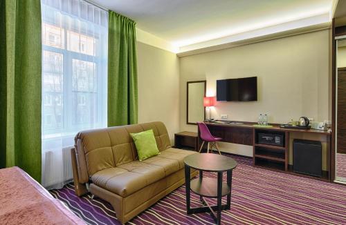 a hotel room with a couch and a table and a tv at Voyage Business Hotel in Saint Petersburg