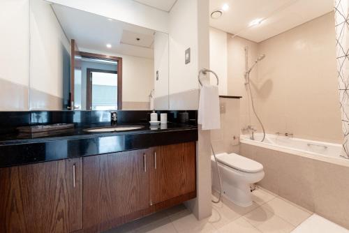 a bathroom with a sink and a toilet and a tub at Lovely 1 Bedroom Apartment, Near Dubai Mall & Burj Khalifa, Downtown Dubai in Dubai