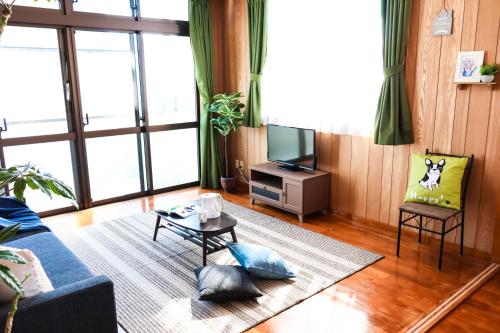 a living room with a blue couch and a tv at Condominium Hotel Mihama Upi in Chatan