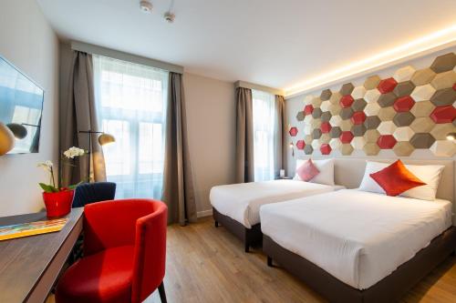 a hotel room with two beds and a red chair at Three Corners Hotel Art in Budapest