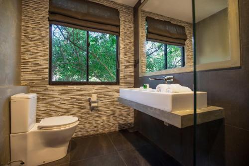 een badkamer met een wastafel, een toilet en een raam bij Kalapuwa Resort in Balapitiya