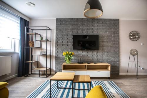 een woonkamer met een tv en een bakstenen muur bij Apartamenty Leśna 1 in Zielona Góra