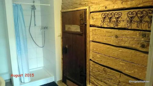 ein Badezimmer mit einer Holztür und einer Dusche in der Unterkunft Schnaitstadlhütte in Krispl