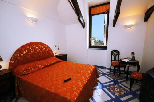 a bedroom with a bed and a chair and a window at Hotel Croce Di Amalfi in Amalfi