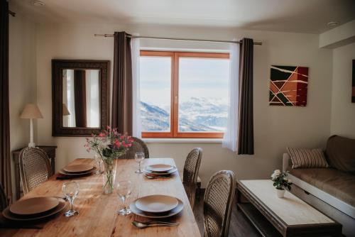 a dining room with a table with chairs and a window at Résidence Sunêlia Les Logis d'Orres in Les Orres
