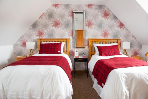 a bedroom with two beds and a mirror on the wall at Ceol na Mara Guest House in Tarbert