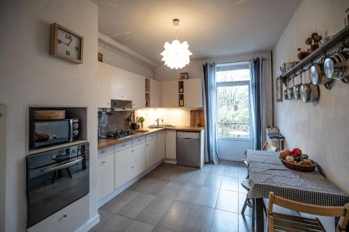 une cuisine avec des armoires blanches, une table et une fenêtre dans l'établissement Bright airy spacious apartment, à Passy