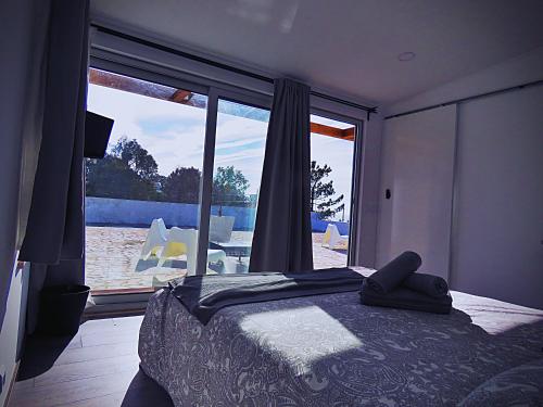 a bedroom with a bed and a large window at Residencia Praia Norte - AL in Nazaré