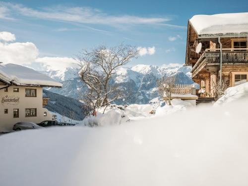 a building covered in snow with mountains in the background at Hanserhof in Zell am Ziller