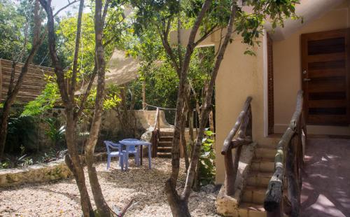 a patio with two chairs and a table and trees at Bungalow Bé La Kin in Cozumel