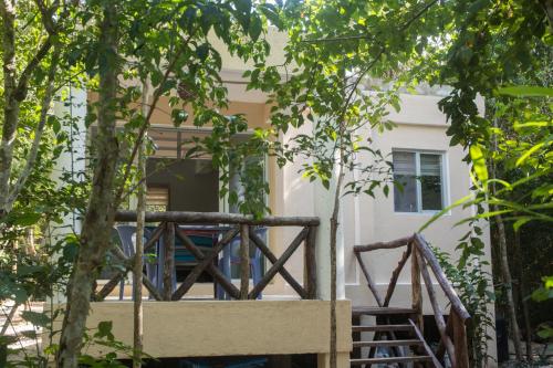 a wooden bridge in front of a building with trees at Bungalow Bé La Kin in Cozumel