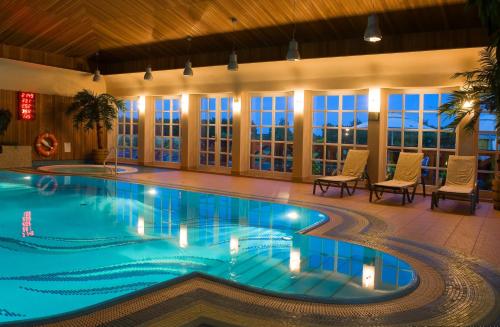 a swimming pool in a hotel with chairs and windows at Hotel Habenda in Budzyń