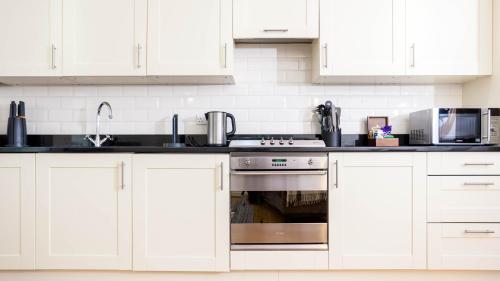 a kitchen with white cabinets and a stainless steel oven at The Highland Club in Fort Augustus