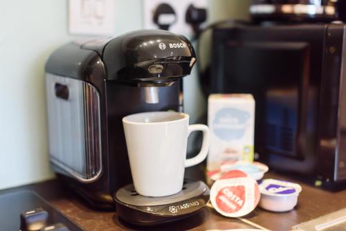 a coffee maker and a cup on a counter at Oakfield Premier Apartments-High Speed WiFi-Smart SelfCheckIn-Central Cardiff Gem in Cardiff