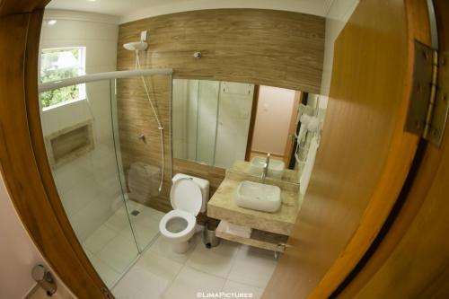 y baño con aseo, lavabo y espejo. en Pousada Villarejo Armação, en Penha