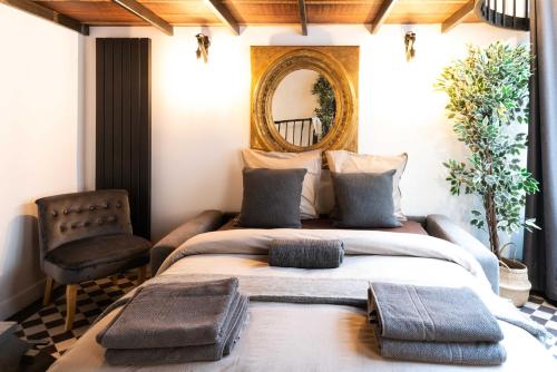 une chambre avec un lit, un miroir et une chaise dans l'établissement Architect's Triplex - Haut Marais, à Paris