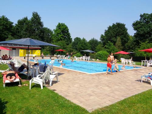 um grupo de pessoas sentadas ao redor de uma piscina em Bungalowpark De Bremerberg em Biddinghuizen