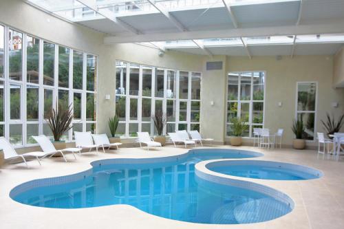 uma piscina num edifício com cadeiras e uma piscina em Hotel Serra da Estrela em Campos de Jordão