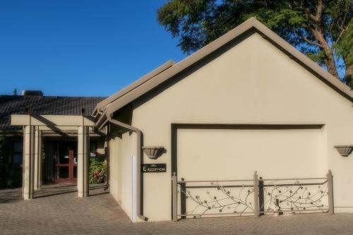 a white building with a large garage door at Mondior Manor Guest House in Kimberley