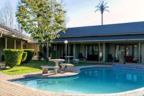 ein Pool mit einer Bank vor einem Haus in der Unterkunft Mondior Manor Guest House in Kimberley