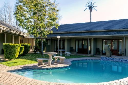 a swimming pool with a bench in front of a house at Mondior Manor Guest House in Kimberley