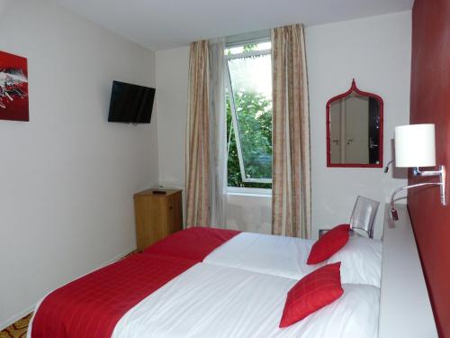 a bedroom with a bed with red pillows and a window at Cit'Hotel Europeen in Angoulême