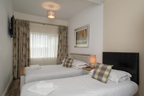 a room with two beds and a table with a window at The Square townhouse Fermoy in Fermoy
