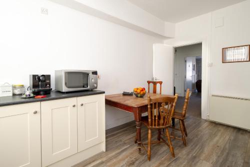 a kitchen with a wooden table and a microwave at The Square townhouse Fermoy in Fermoy
