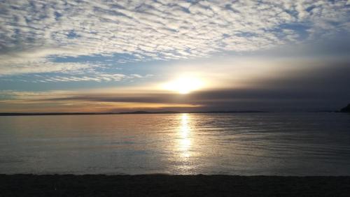 a sunset over a body of water with the sun setting at Apartment Rio in Podstrana