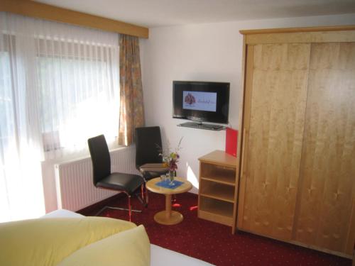 a hotel room with a bed and a tv and chairs at Lärchenhof Serfaus in Serfaus