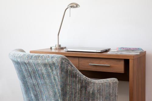 a desk with a laptop and a chair with a lamp at HQ Aparthotel Farnborough in Farnborough