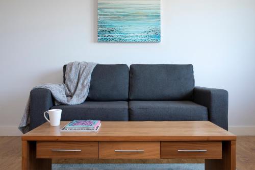 a blue couch sitting next to a wooden coffee table at HQ Aparthotel Farnborough in Farnborough