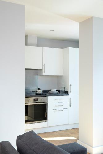 a kitchen with white cabinets and a stove at HQ Aparthotel Farnborough in Farnborough