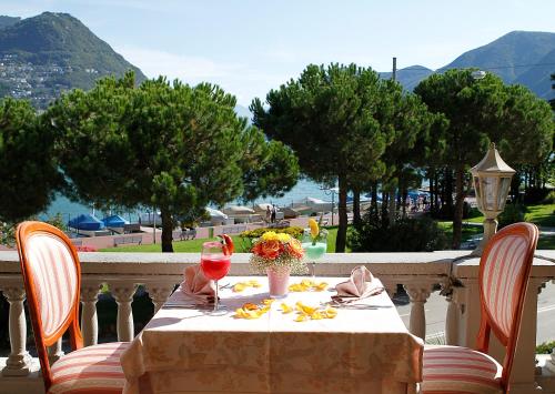 a table with flowers and a glass of wine on a balcony at Hotel Victoria in Lugano