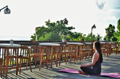 a woman sitting on a yoga mat in front of a bar at Ocean Terrace Suite And Spa Luxury in Nusa Penida