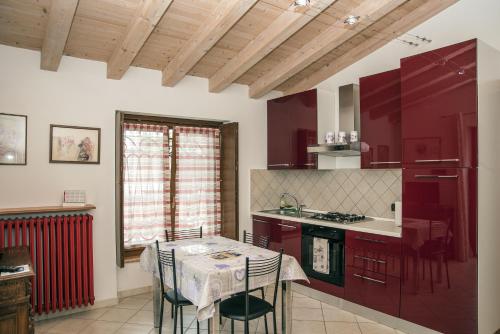a kitchen with red cabinets and a table with chairs at Residence Villa Vinco in Tregnago