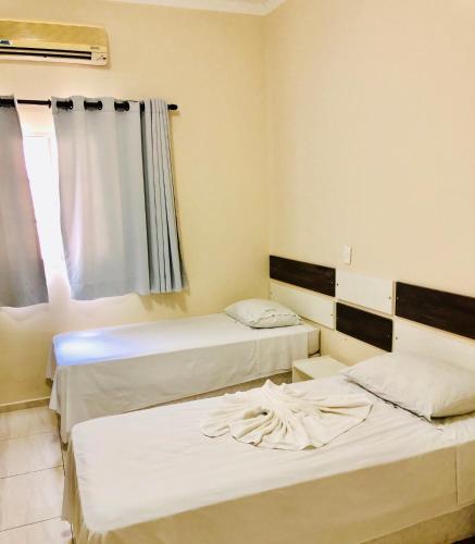 2 Betten in einem Zimmer mit Fenster in der Unterkunft Porto Verde Hotel in Lins