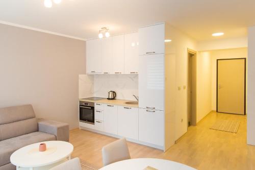 cocina con armarios blancos, sofá y mesa en Central Budva apartment, en Budva