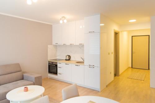 a kitchen with white cabinets and a couch and a table at Central Budva apartment in Budva