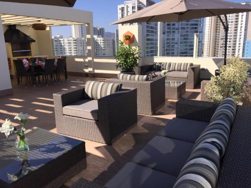 a rooftop patio with chairs and tables and an umbrella at Sector Enjoy Premium Frente al Mar in Coquimbo