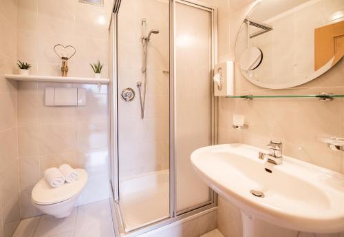 a bathroom with a shower and a sink and a toilet at Vitaurina Royal Hotel in Molini di Tures