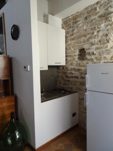 a kitchen with white cabinets and a white refrigerator at Non ditelo al Duca - La Cappuccina in Spoleto