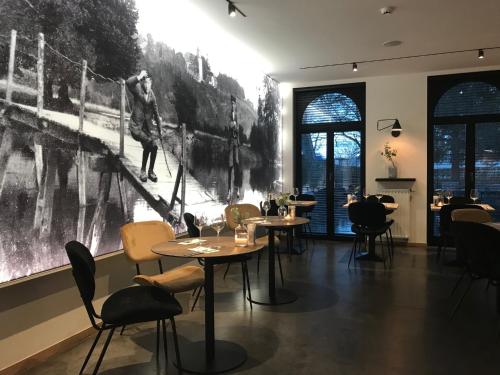 a restaurant with tables and chairs and a large painting on the wall at Hotel La Passerelle in Grandhan