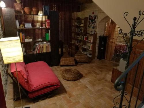 a living room with a red chair and book shelves at Il nido della rondine, appartamento nel borgo medievale in Cartoceto