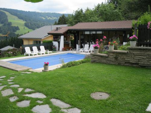 a backyard with a swimming pool and a house at Le Logis du Chalet Perce-Neige in Châtel-Saint-Denis