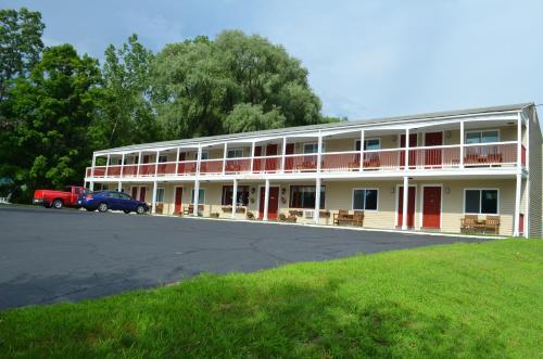 a large white building with red doors and a parking lot at Cozy Corner Motel in Williamstown
