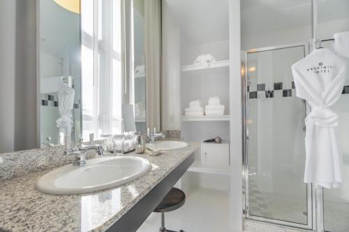 a white bathroom with two sinks and a shower at Proximity Hotel in Greensboro
