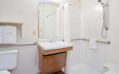 a white bathroom with a sink and a shower at WoodSpring Suites Holland - Grand Rapids in Holland